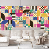 A modern living room with a beige sofa and round coffee table is set against Cover-Alls’ Bauhaus Tile Wallpaper, creating vibrant energy—ideal for anyone looking for striking tile wallpaper or contemporary wallpaper rolls.