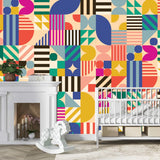 A nursery with a white crib, modern white fireplace, wooden rocking horse, and the wall covered in Cover-Alls’ Bauhaus Tile Wallpaper featuring a bold geometric pattern.