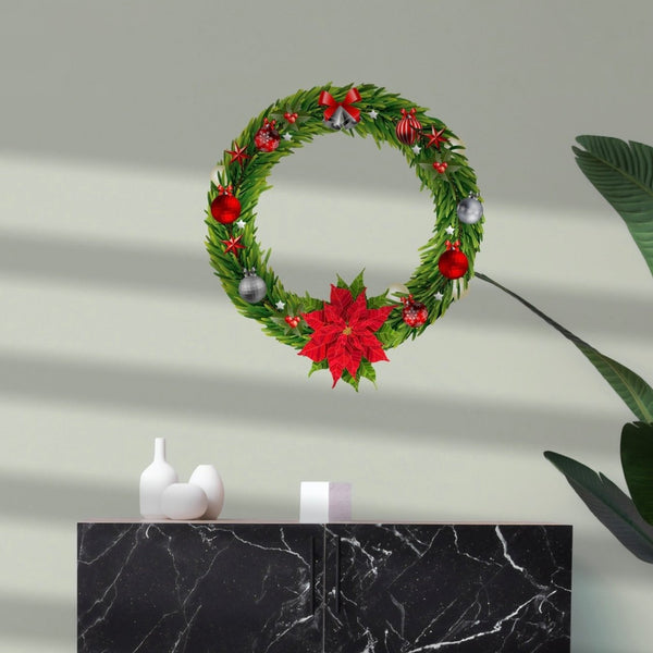 A Cover-Alls Christmas wreath decal with green foliage, red berries, and poinsettias hanging on a gray wall, above a black marble cabinet with two white vases.