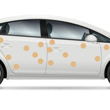 White sedan car with vibrant orange Cover-Alls Dot Decals, profile view, isolated on a white background.