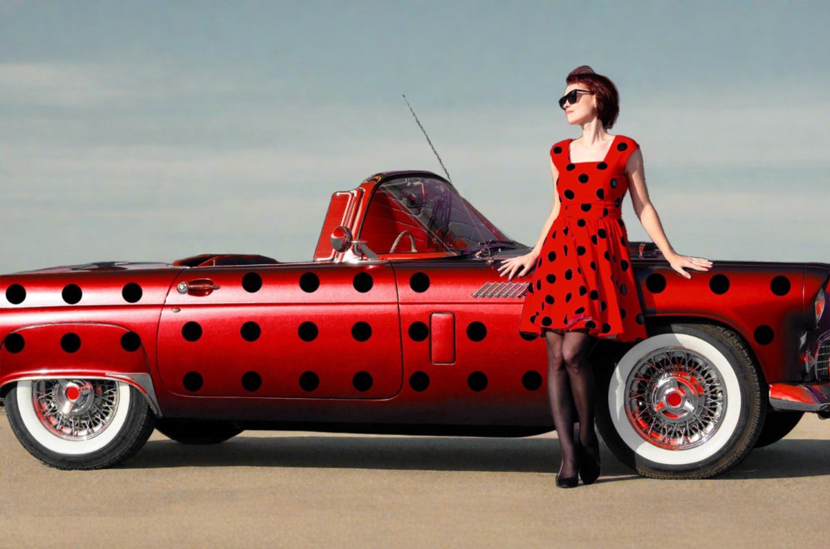 A woman in a red polka dot dress and sunglasses leaning on a red car with Cover-Alls Dot Decals, standing in front of a building.