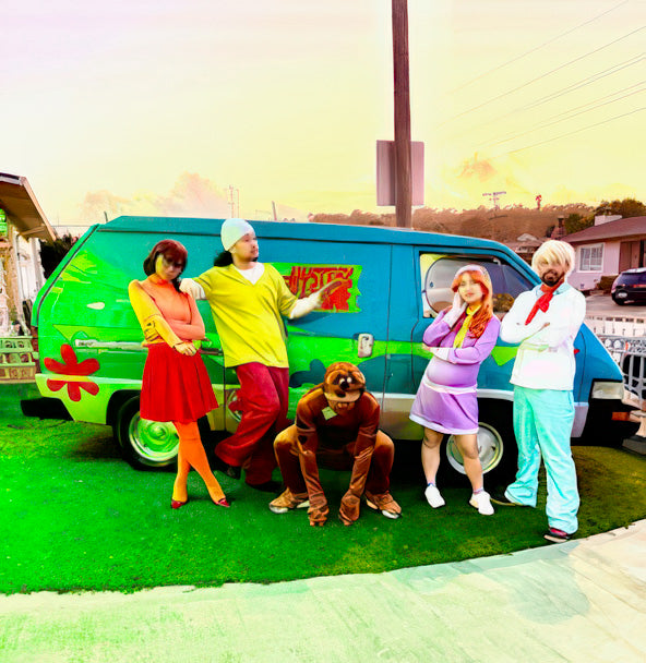 Five people in colorful costumes pose by a green and blue van decorated with Cover-Alls’ Mystery Machine Kit, bringing to life the classic Scooby-Doo cartoon characters.