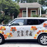White SUV decorated with colorful Day of the Dead Mariachi Band-themed decals, including sugar skulls, parked in front of a house.