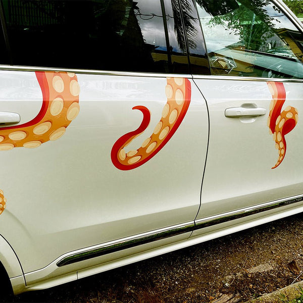 A white car embellished with a Eight Terrifying Tentacle Decals featuring orange and red octopus tentacles along its side by Cover-Alls.
