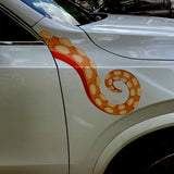 A silver car with Eight Terrifying Tentacle Decals by Cover-Alls, featuring a decorative red and orange giant squid tentacle design on the door, parked on a street.