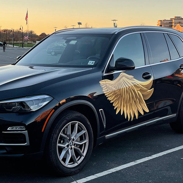 A black BMW SUV with large Cover-Alls Gold Wing Decals decoration on its front door, parked in a lot during sunset.