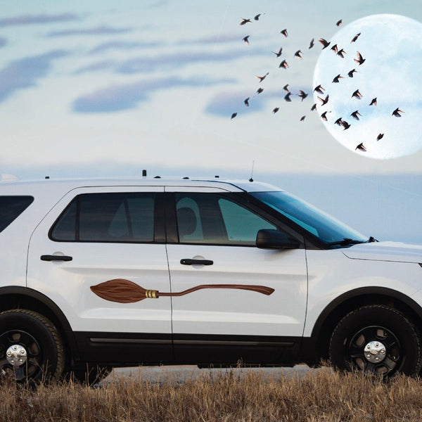A white SUV with a Cover-Alls Magical Broomstick decal parked in a field under a full moon with birds flying in the background.