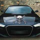 Black car with a Cover-Alls Skull & Crossbone Decal on the hood, parked in front of a graffiti-covered wall.