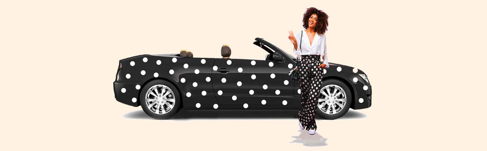 Woman in polka dots next to polka dot convertible