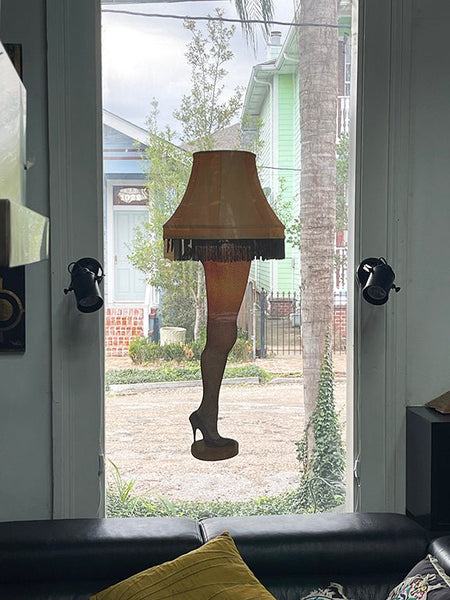 View from a window featuring a Cover-Alls Leg Lamp decal with a fringed shade, set between two black wall lamps, overlooking a street with colorful houses.