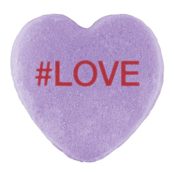 A purple three-dimensional heart-shaped Candy Hearts for Pride with the hashtag "#love" printed in red on its surface by Cover-Alls.