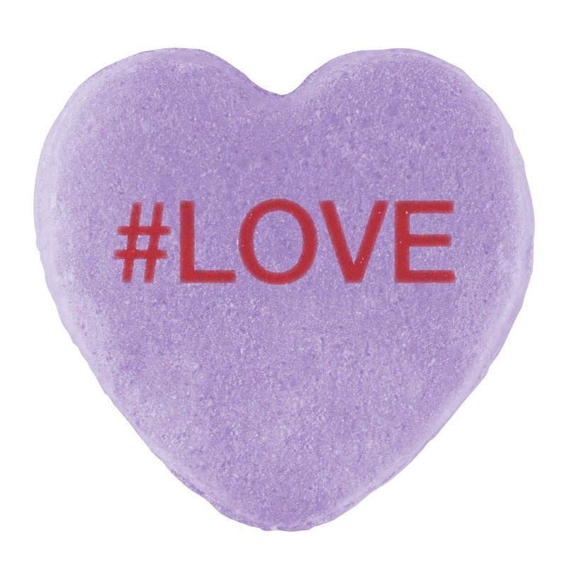 A purple three-dimensional heart-shaped Candy Hearts for Pride with the hashtag "#love" printed in red on its surface by Cover-Alls.