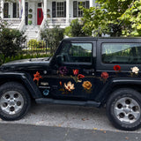 A black Jeep Wrangler parked on a gravel path with Cover-Alls Dark Romance Vintage Flower Decals on its side, in front of a row of white houses with porches and greenery.