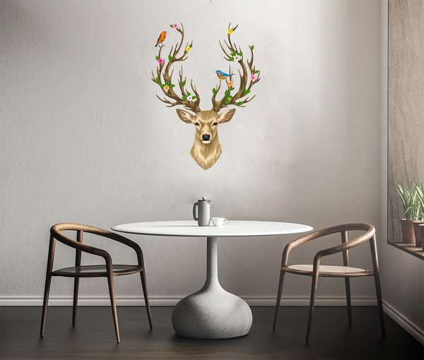 A small dining area with a round white table, two brown chairs, and a decorative Deer Head with Antlers, <br>Flowers and Birds from Cover-Alls on the wall above. A mug is placed on the table.