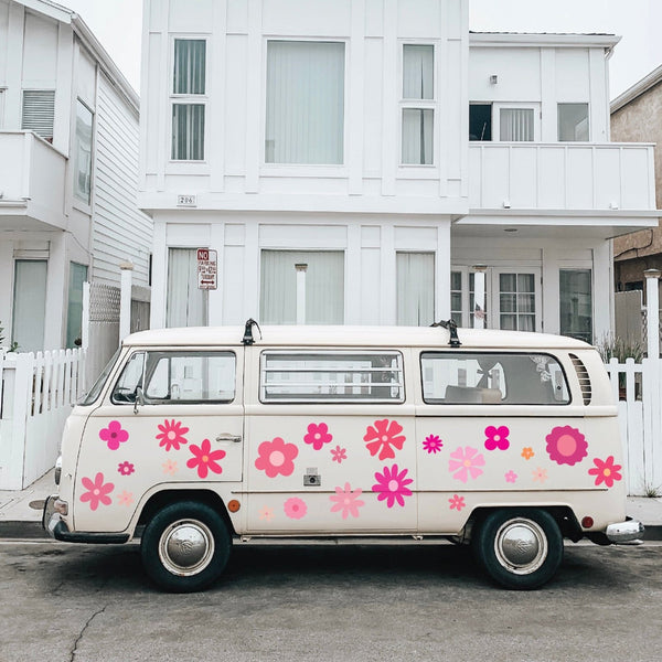 A vintage white van decorated with Cover-Alls Pink Flower Power style flowers parked outside a modern white two-story house.