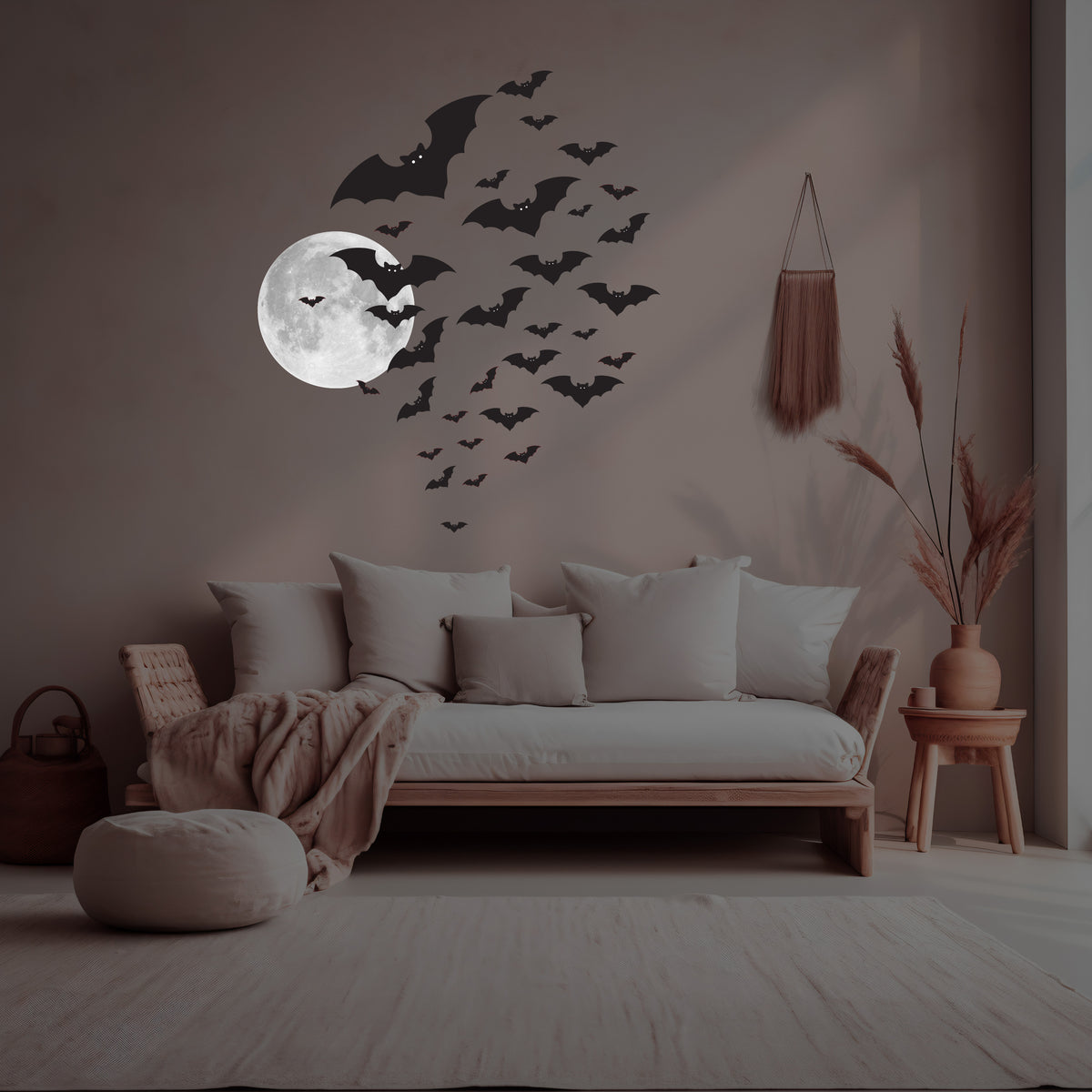 A minimalist living room features a wall adorned with reusable bat decals and the Silver or Yellow Moon Decal by Cover-Alls, adding a celestial touch. A cozy couch with pillows and a throw blanket is the focal point, accompanied by a pouf and a side table with decor.