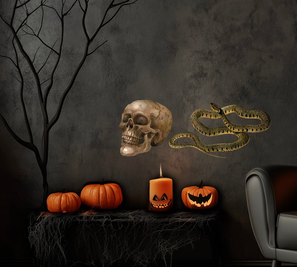 A Halloween scene with Dark Flowers, a skull, a Cover-Alls Striped Vintage Snake Decal, pumpkins, lit candles, and a dark, bare tree on a table next to a gray armchair against a dark wall.