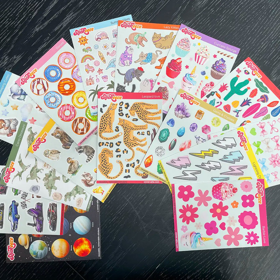 Assorted colorful reusable stickers displayed on a dark wooden surface, featuring various designs like animals, flowers, and planets from Kid's Sticker Club by Stickeeze.