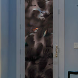 The Zombies Glass Window Decal by Cover-Alls, featuring multiple handprints and face impressions on foggy glass, creates an eerie effect that's perfect for horror decoration. When applied to a door framed by a light-colored wall in a dimly lit room, it adds an unsettling Halloween decor touch.