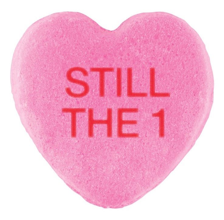 A pink Cover-Alls candy heart with the phrase "still the 1" embossed in red letters, specially made for Valentine's Day.