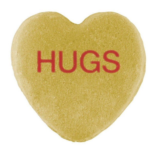A heart-shaped sugar cookie with a Candy Hearts design and the word "hugs" printed in red icing at the center.
