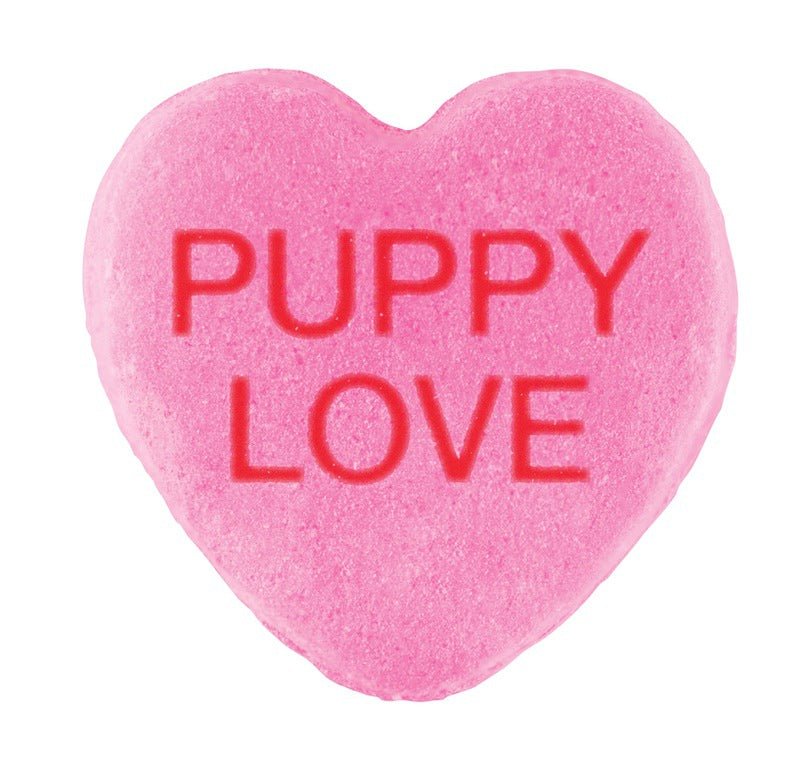 A pink heart-shaped Candy Hearts with the phrase "puppy love" embossed in red letters, featuring a custom design for Valentine's Day by Cover-Alls.