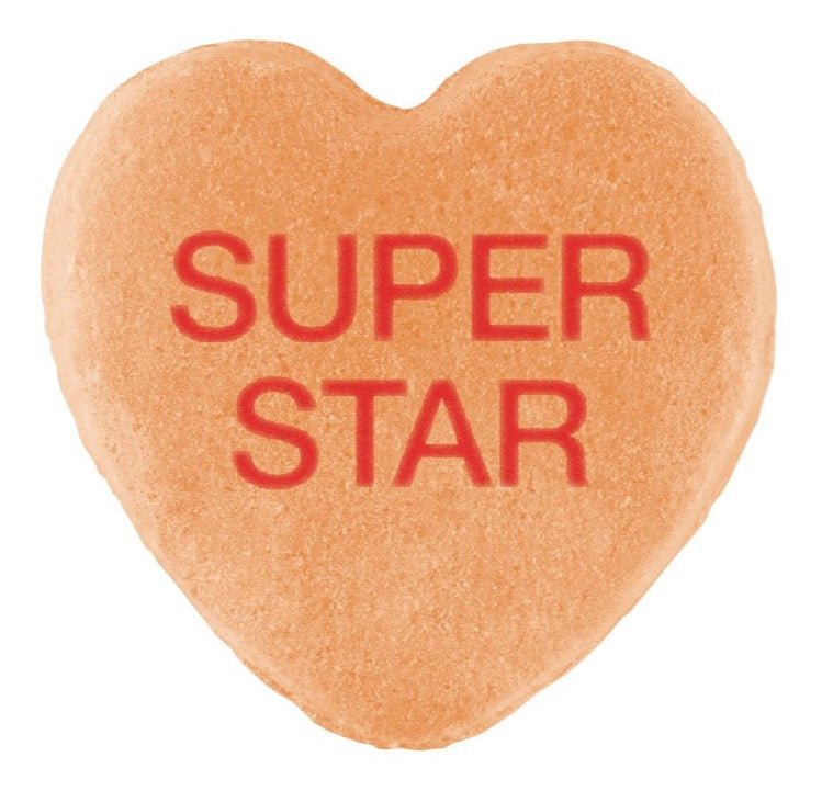 A heart-shaped Candy Hearts in a light orange color with a Cover-Alls design stamped in red across it.