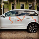 A white SUV with Eight Terrifying Tentacle Decals, featuring Halloween themed decals, parked in front of a house.