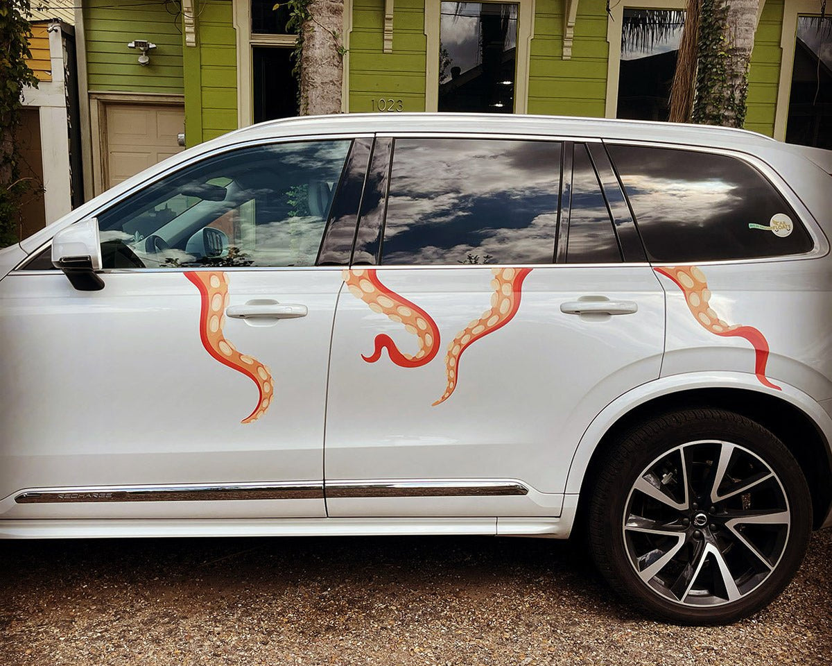 A white SUV with Eight Terrifying Tentacle Decals, featuring Halloween themed decals, parked in front of a house.